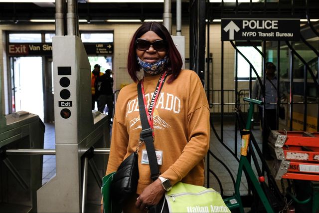 A woman stands in front of subway turnstiles